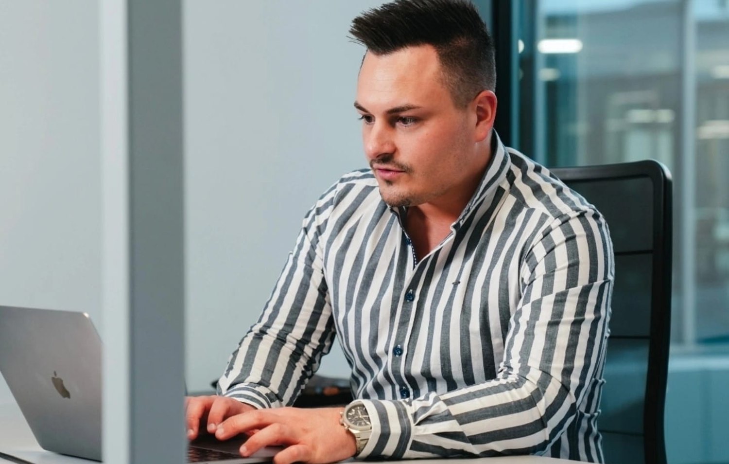 Dennis Hampe arbeitet an einem MacBook im Büro